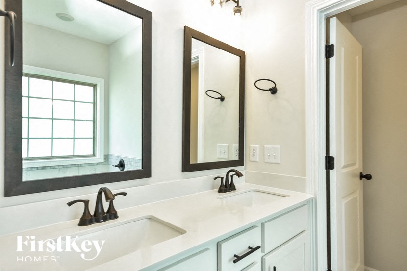 a white bathroom with two sinks and two mirrors