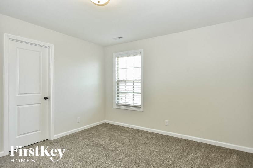 a bedroom with white walls and a white door and a window