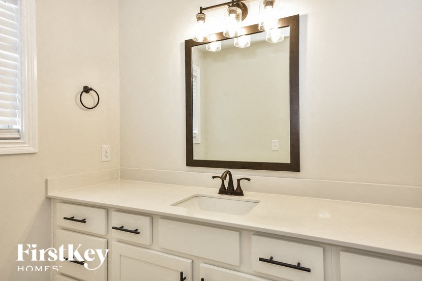 a bathroom with white cabinets and a sink and a mirror