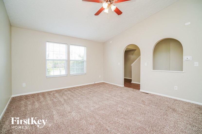 A spacious room with a carpeted floor and a ceiling fan.