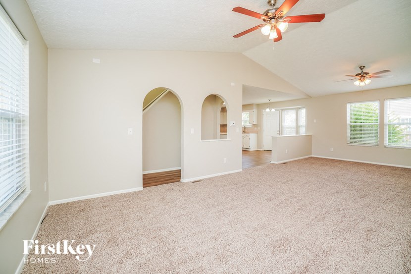 A spacious room with a ceiling fan and arched doorways.