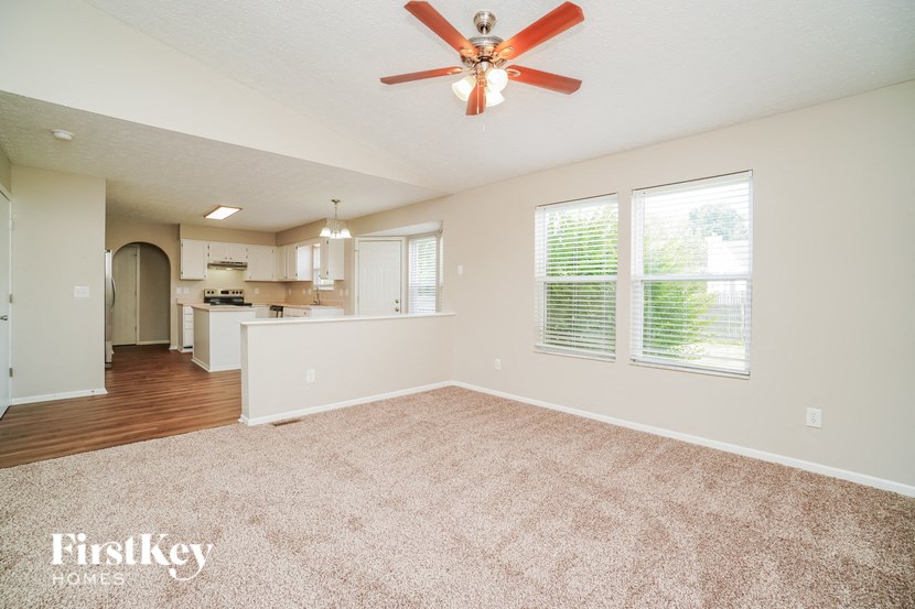 A spacious room with a ceiling fan and carpeted floor.