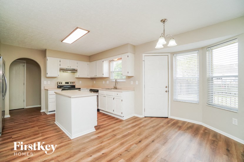 A kitchen with wooden floors and white appliances.
