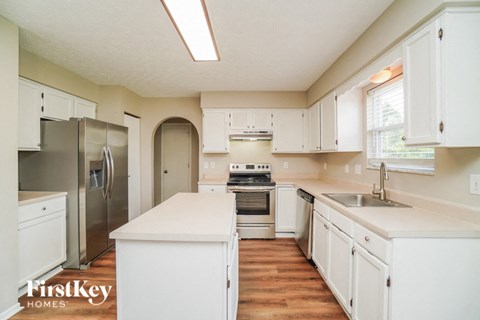 A kitchen with white cabinets and a stainless steel refrigerator.