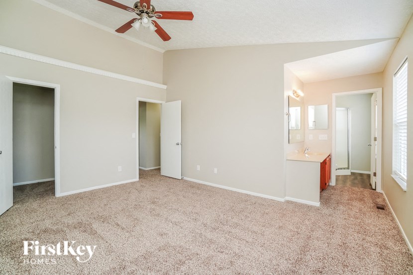 A spacious room with a ceiling fan and a carpeted floor.