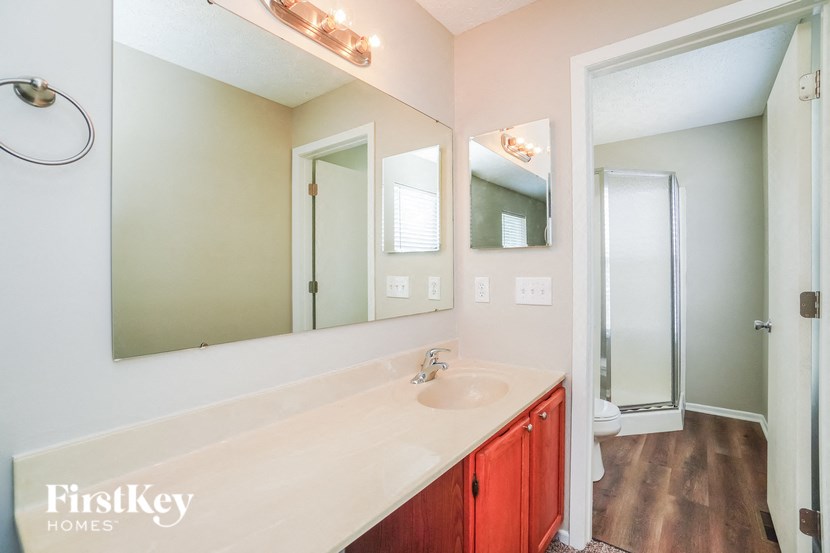 A bathroom with a sink, mirrors and a shower.