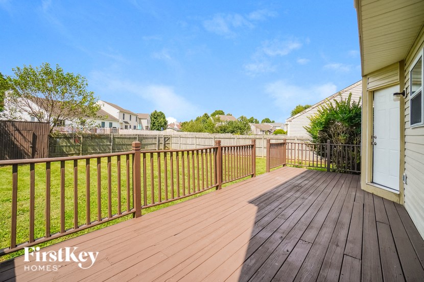 A wooden deck with a railing and a white door.