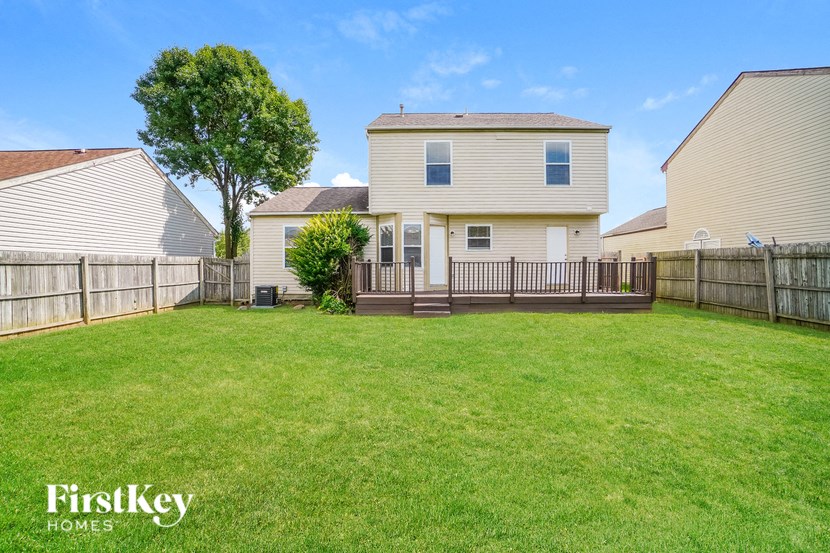 A house with a fence and a tree in the yard.