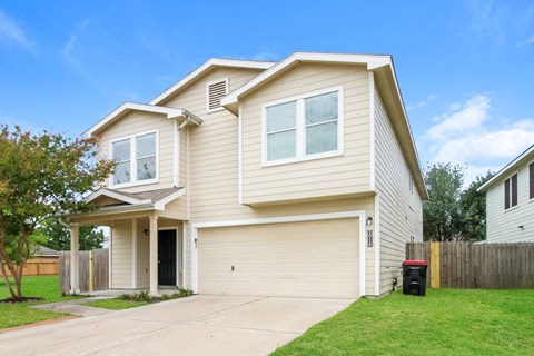 a beige house with a driveway and a yard