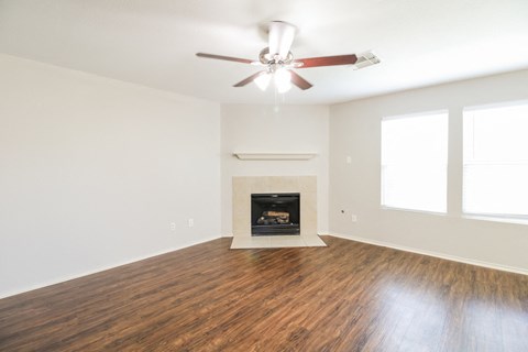 an empty living room with a ceiling fan and a fireplace