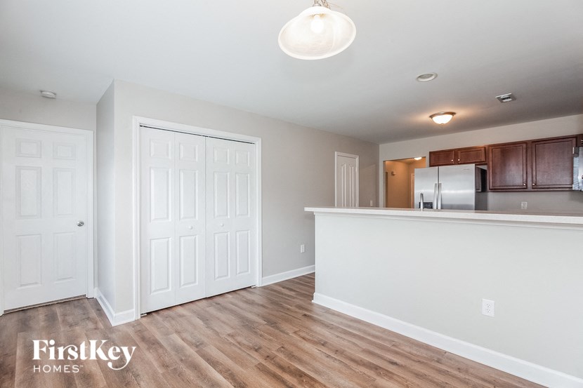 a kitchen and living room with a white wall and wood flooring