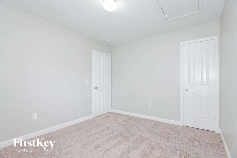 a white bedroom with two doors and a carpeted floor