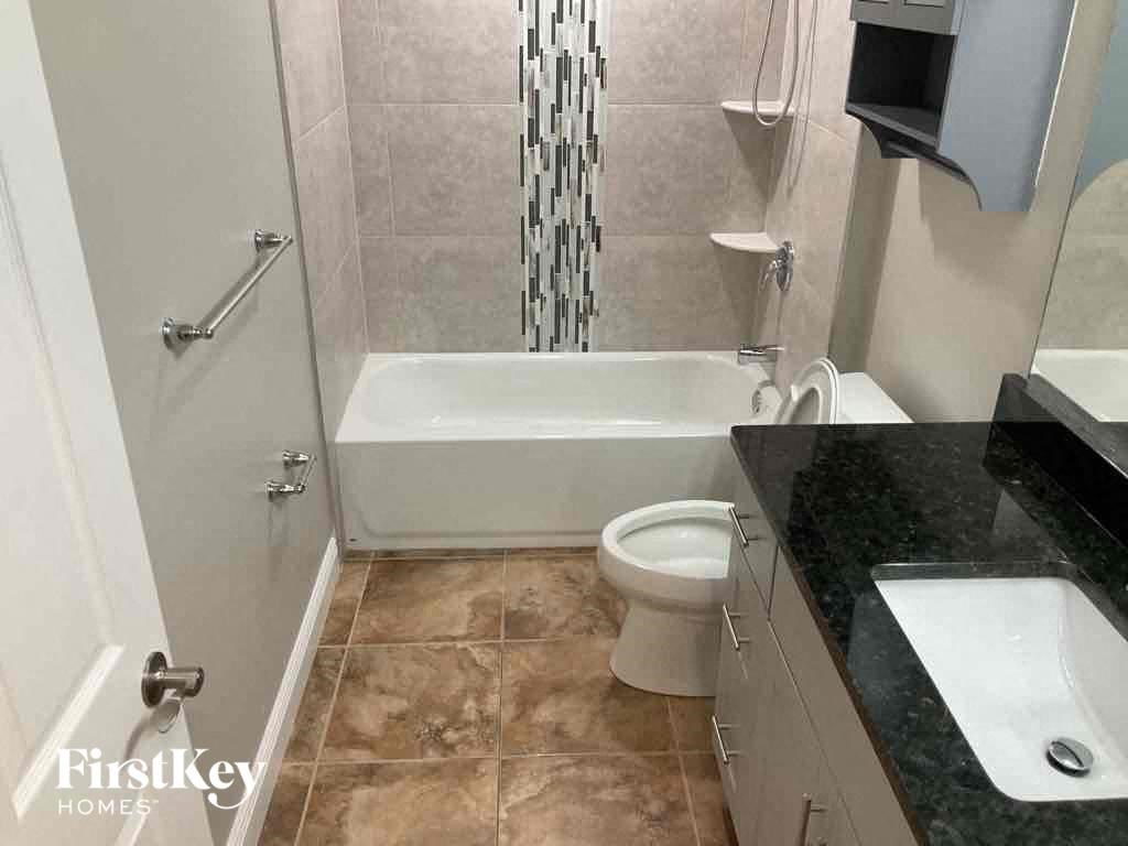 A tiled bathroom with a white tub and toilet.