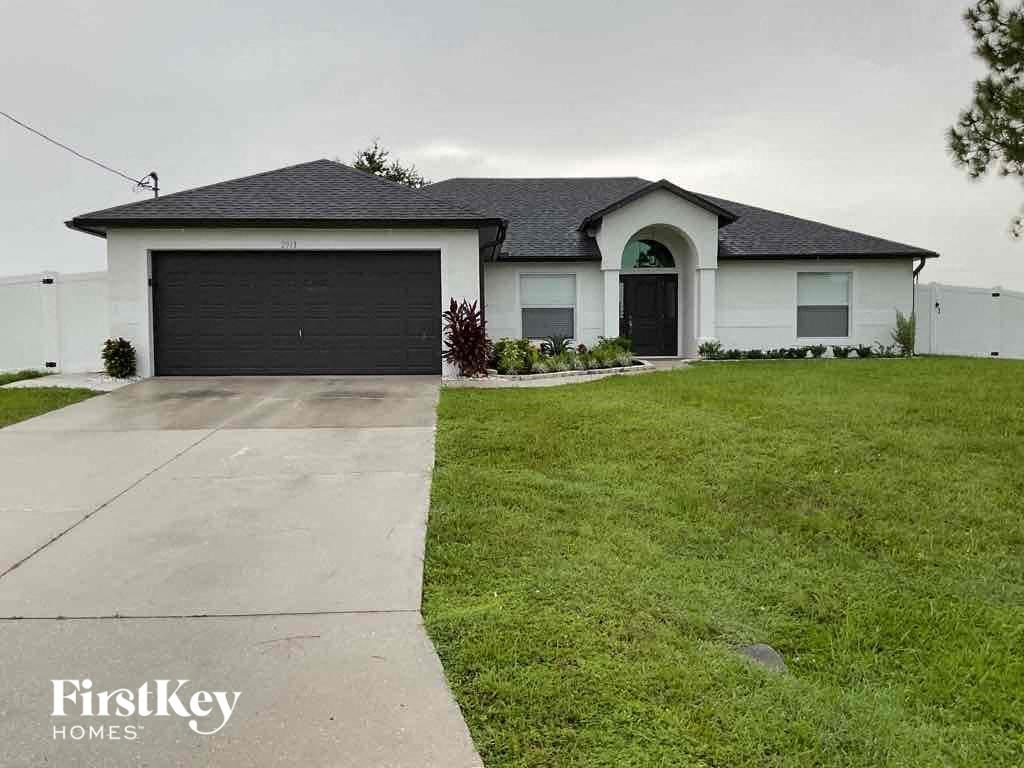 A white house with a black garage door is for sale.