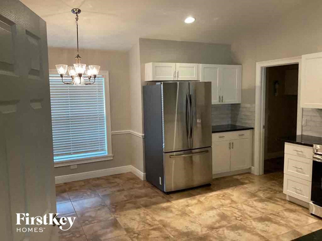 A kitchen with a stainless steel refrigerator and a chandelier.