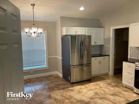A kitchen with a stainless steel refrigerator and a chandelier.