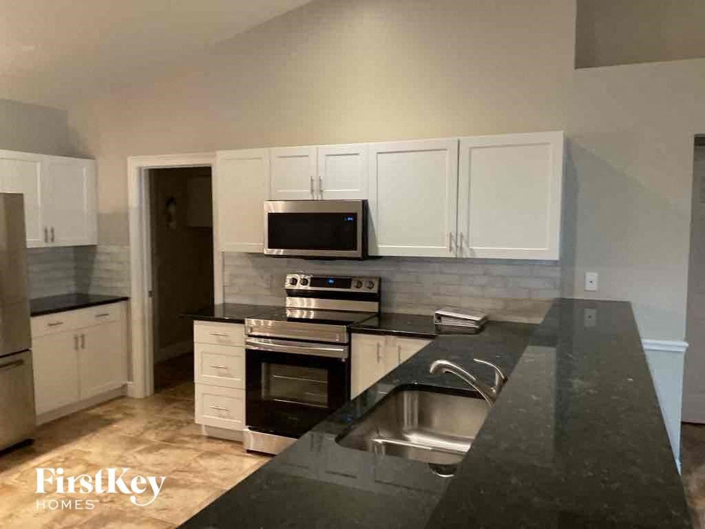 A kitchen with a black countertop and white cabinets.
