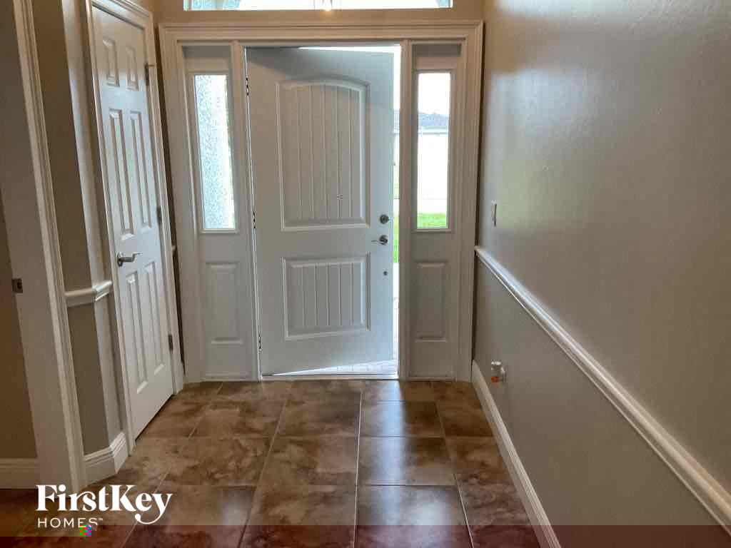 A hallway with a tiled floor and a white door.