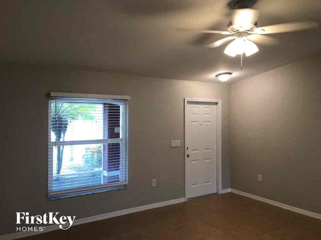 a living room with a white door and a ceiling fan