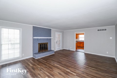 a living room with a brick fireplace and wooden floors