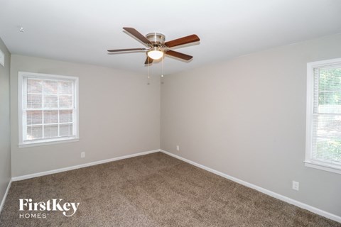 a bedroom with carpet and a ceiling fan and two windows