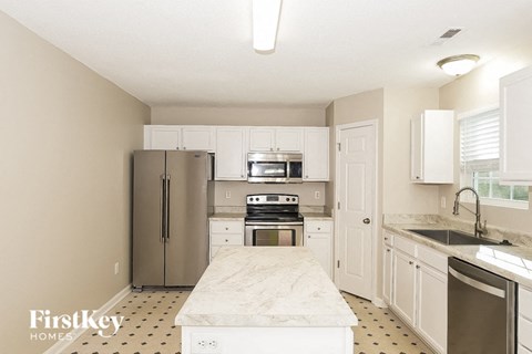 A kitchen with a marble countertop and a refrigerator.