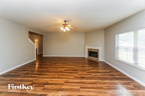 an empty living room with a ceiling fan and a fireplace