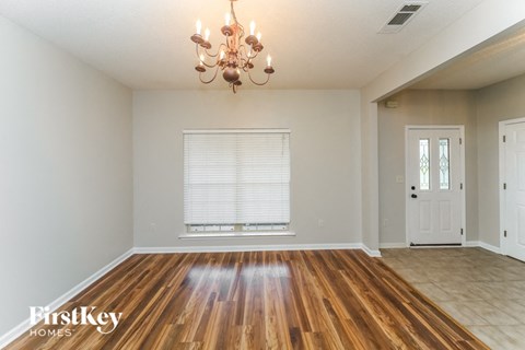 the living room and dining room with wood flooring and a chandelier