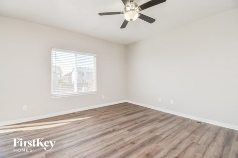 A room with a ceiling fan and wooden flooring.
