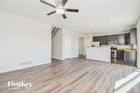 A spacious kitchen and living room with wood flooring and a ceiling fan.