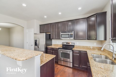 A kitchen with dark brown cabinets and a granite countertop.