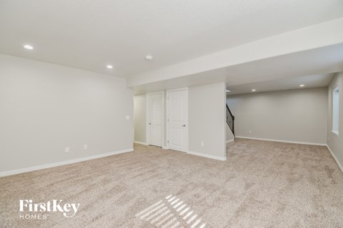 A spacious room with a carpeted floor and a closet with a door.
