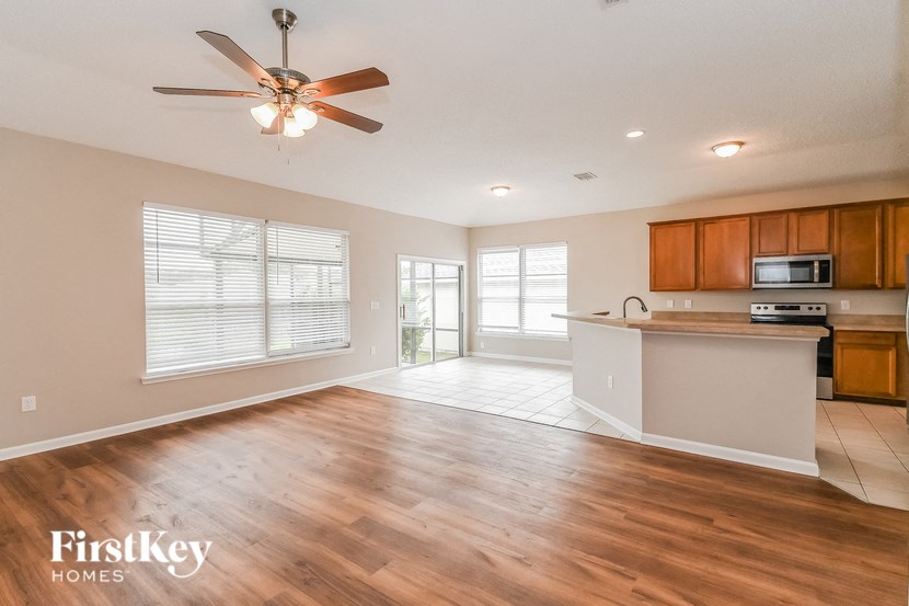 A spacious living room with wooden floors and a ceiling fan.