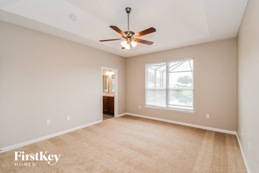 A spacious room with a ceiling fan and a window with blinds.