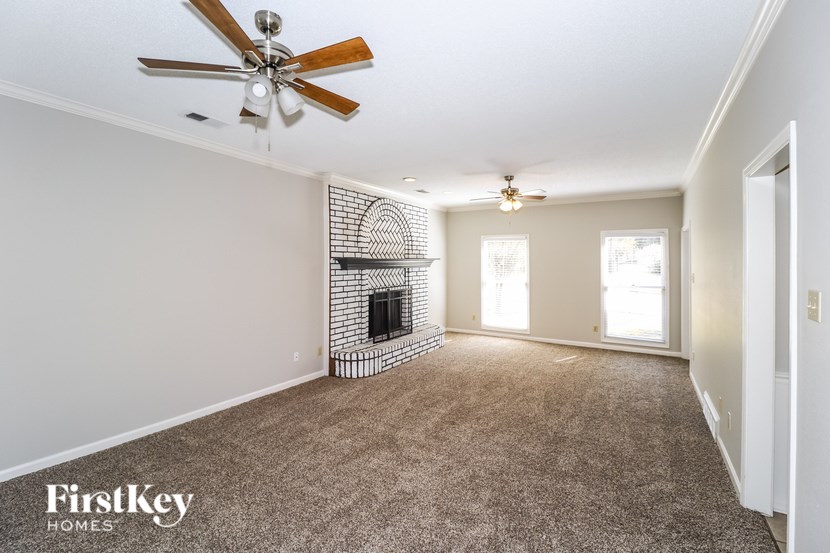A spacious room with a fireplace and a ceiling fan.