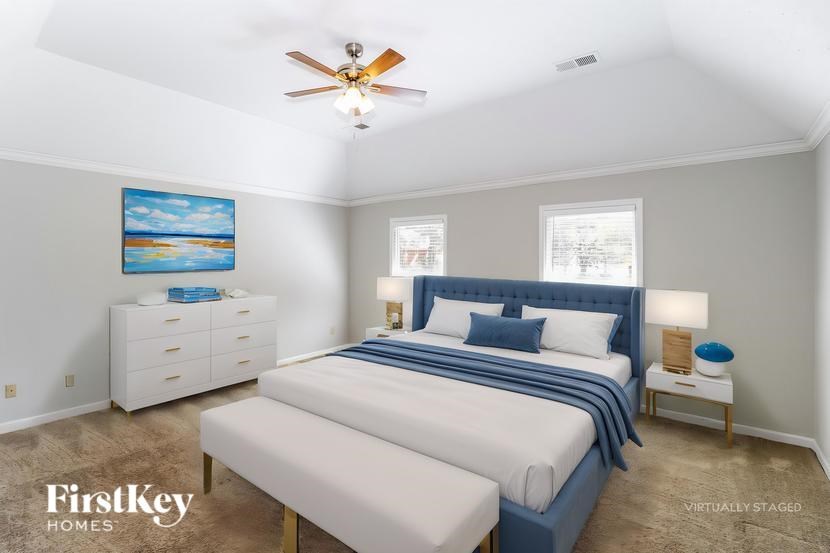 A bedroom with a large bed and a ceiling fan.