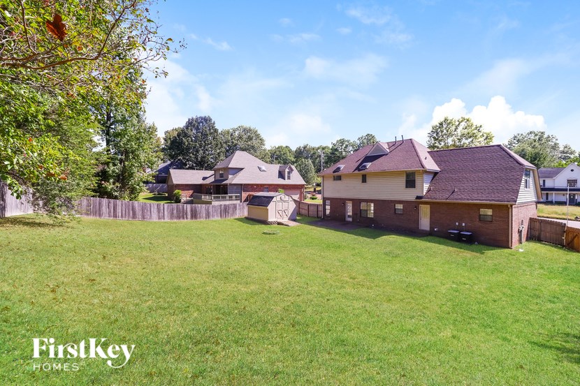 A grassy field with a house and a fence in the background.