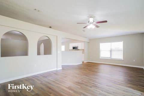 A spacious room with wooden floors and a ceiling fan.