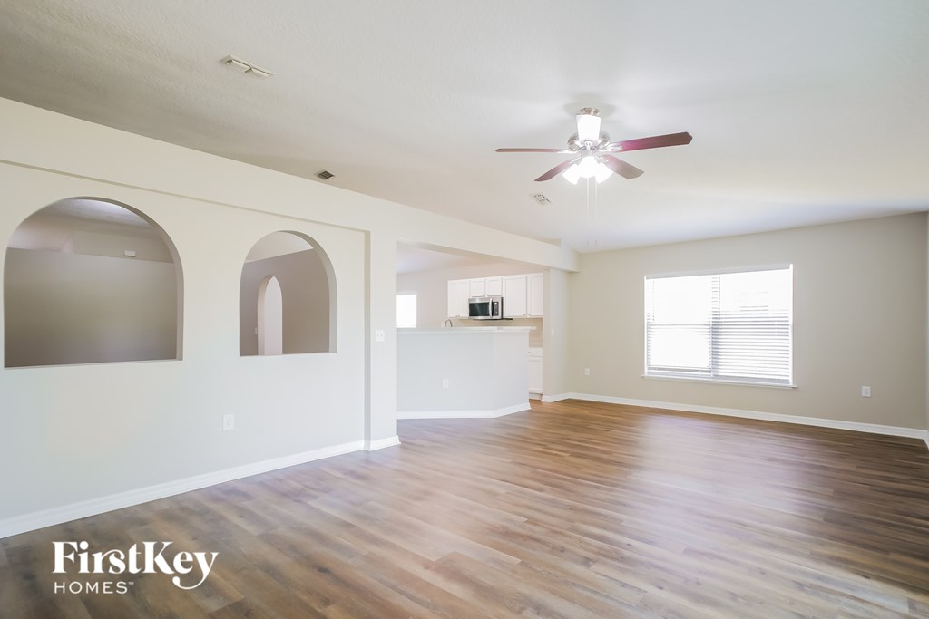 A spacious room with wooden floors and a ceiling fan.