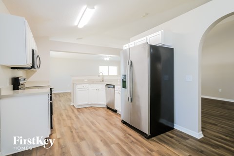 A kitchen with a black fridge and white cabinets.