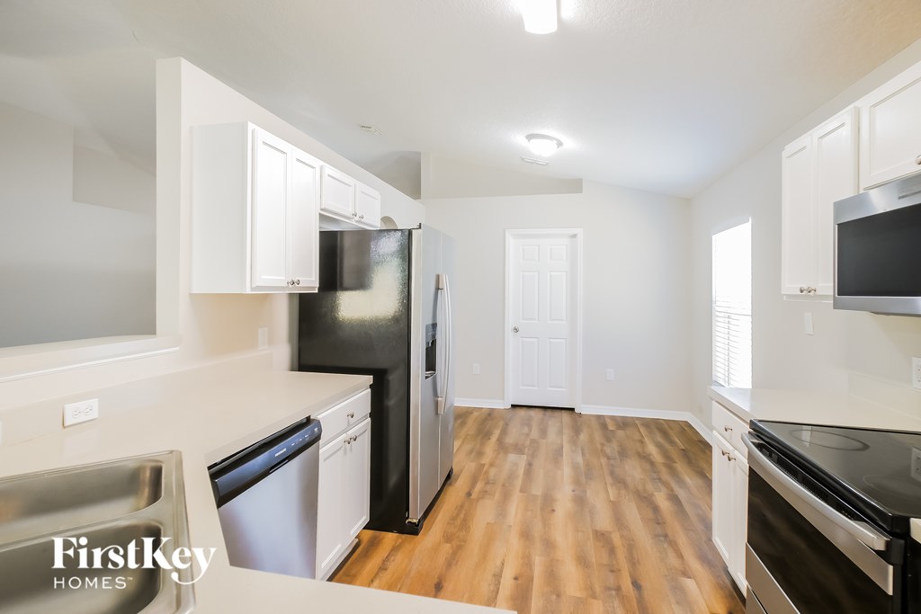 A kitchen with wooden floors and white cabinets.