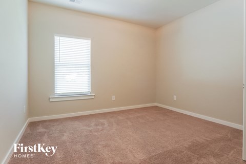 a bedroom with a window and a carpeted floor