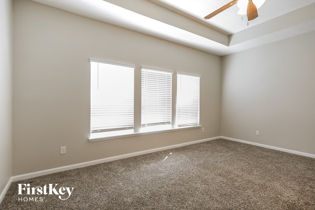 a empty room with three windows and a ceiling fan