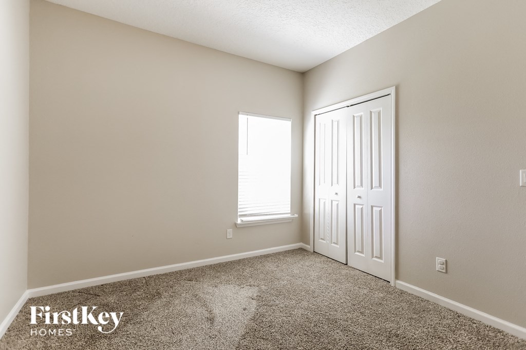 a bedroom with carpet and a white door and window