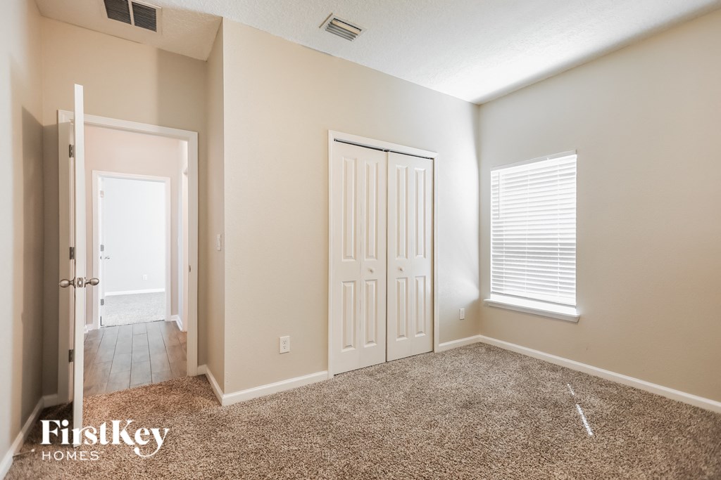 a bedroom with a carpeted floor and a white door and window
