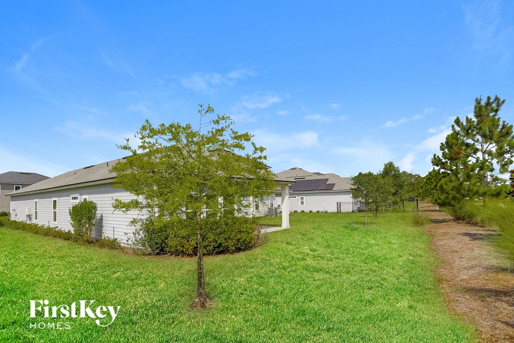 the backyard of a white house with trees and grass