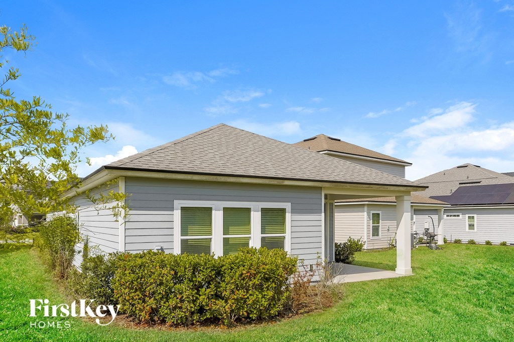 a small gray house with green grass and a blue sky