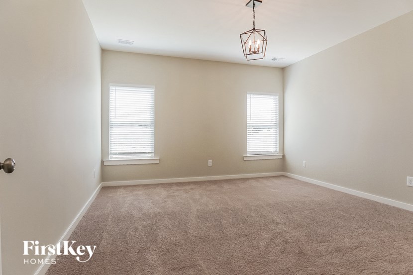 a carpeted living room with two windows and a lamp