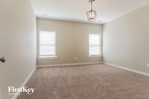 a carpeted living room with two windows and a lamp