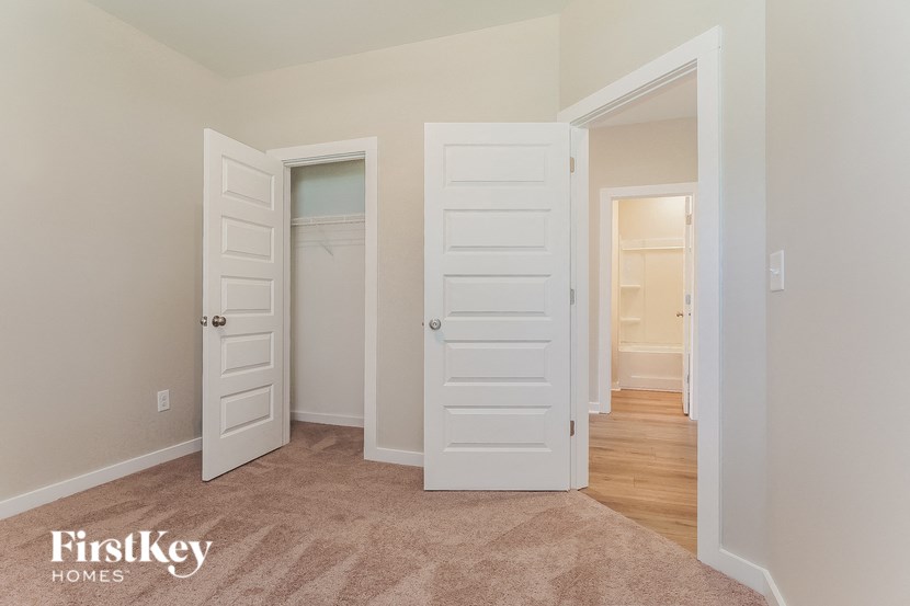 a bedroom with two white doors and a hallway to a closet